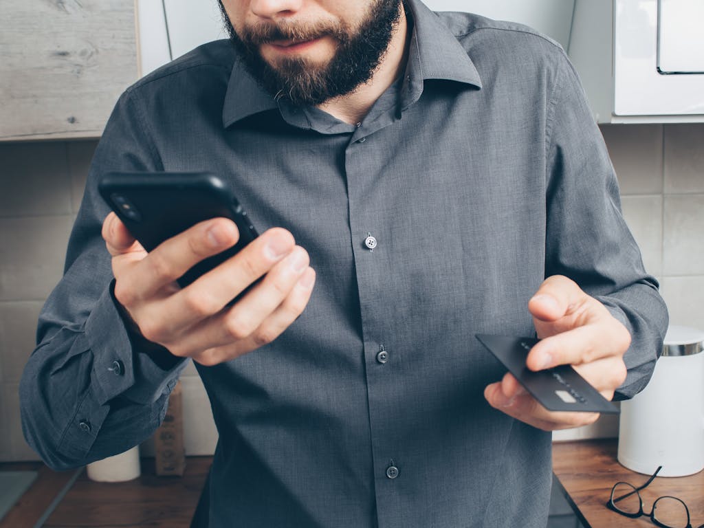 Man in Gray Button Up Long Sleeve Shirt Holding Black Smartphone